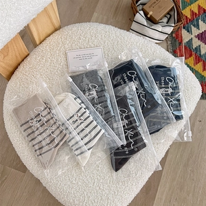 Detail of 5-pack striped crew socks in individual zipper bags on a cozy white soft stool