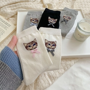 Detailed close-up of cute cat embroidery and decorative bows on rib-knit cotton socks