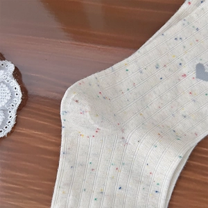 Close-up of knit crew socks with colorful speckled texture and grey heart pattern