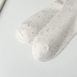 Detail of white knit socks with colorful speckled texture and fine toe stitching