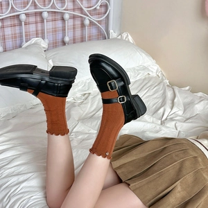 Close-up of black platform Mary Jane shoes with double straps and brown knit socks