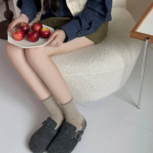 Detail of fine striped cotton socks paired with dark grey buckled wool felt clogs