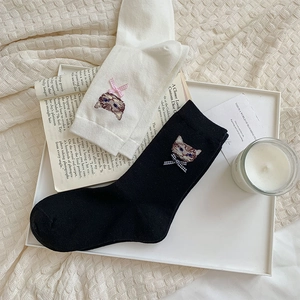 Detail of cute cat embroidery and checkered bow on white and black cotton mid-tube socks