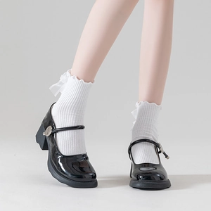 Detail of white ruffle lace socks paired with black patent leather Mary Jane shoes