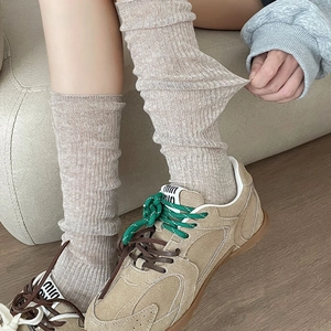 Close-up of oatmeal vertical ribbed knit socks paired with retro patchwork sneakers