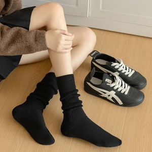 Detail of black ribbed knit crew socks showing fine texture and mid-calf slouchy style