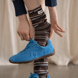 Close-up of blue suede retro sneakers and striped crew socks with woven brand label