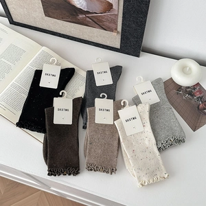 Close-up of six pairs of knitted crew socks with ruffled edges and speckled texture