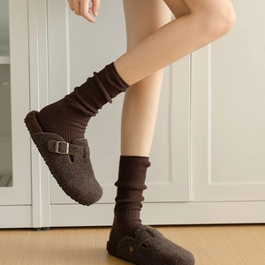 Detail view of dark brown felt mules with wool lining and ribbed knit socks on feet