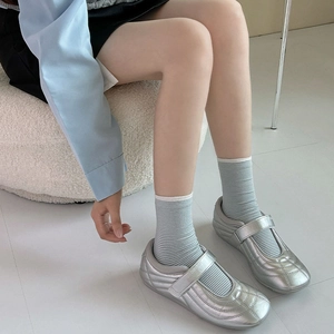 Silver metallic Mary Jane sneakers with striped socks on minimalist background