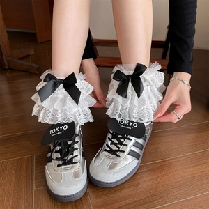 Sweet Lolita white lace socks with layered ruffles and black bows worn with silver shoes