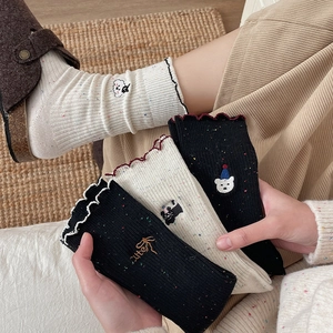 Detail of speckled ruffle socks featuring cute animal embroidery and wavy lace cuffs