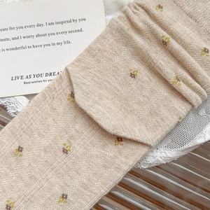 Close-up of beige knit socks featuring delicate floral embroidery and soft texture
