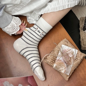 Detail of cream striped socks featuring bee embroidery and letter detail on cotton fabric