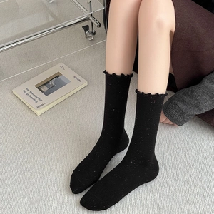 Detailed close-up of black slouch socks with colorful Donegal spots and ruffled edges