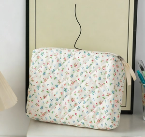 Detail of quilted makeup bag with floral pattern, diamond stitching and ribbon zipper pull
