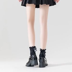Detail of Lolita ruffled socks with bow design paired with glossy leather shoes