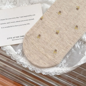 Close-up of beige cotton socks with yellow floral patterns on soft lace background