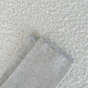 Detail of grey and white striped knit sock with elastic ribbed cuff on soft white background