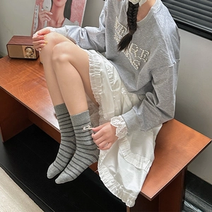 Detail of gray striped crew socks with Bee label paired with a white ruffled skirt