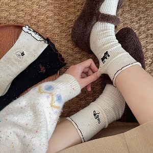 Close-up of cute cartoon embroidery on speckled knit socks with scalloped edges