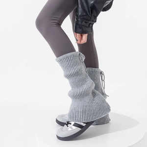 Detail of grey knitted leg warmers with drawstring ties and vertical ribbed texture