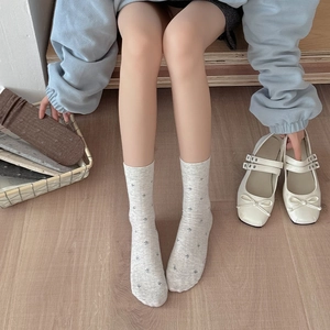 Detailed knit texture of gray floral mid-calf socks paired with cream Mary Jane shoes