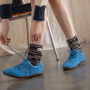 Close-up of retro striped slouch socks with fabric label paired with blue suede sneakers