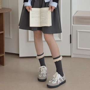 Detailansicht dunkelgraue Socken mit beigem Lammfellsaum und Fransen im süßen Stil