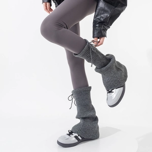 Detailed knit of dark gray leg warmers with adjustable drawstring and ribbed texture