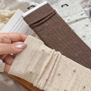 Detail of vintage floral knit mid-calf socks with vertical ribbed texture and embroidery