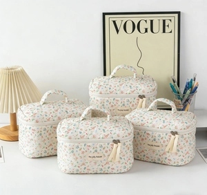 Detail of four-piece quilted floral makeup bag set with metal zippers and carry handles