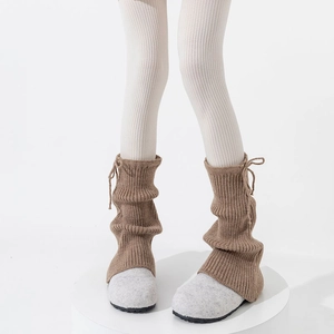 Detail of ribbed knit leg warmers with drawstring ties in camel brown color