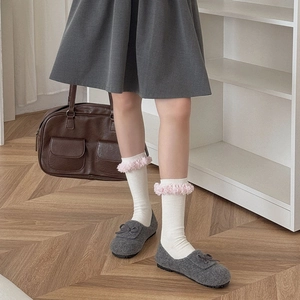 Detailansicht grauer Filz-Loafer mit Schleife und weißen Socken mit rosa Fransenrand