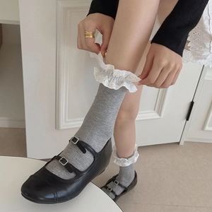 Detail of grey ribbed cotton socks with white lace heart pattern edges and Mary Jane shoes