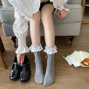 Detail of grey calf-length socks featuring white lace trim and delicate bow accent