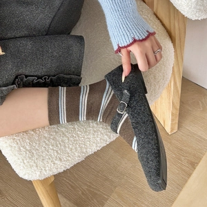 Detail of vintage grey tweed Mary Jane flats with brown and blue striped knit socks