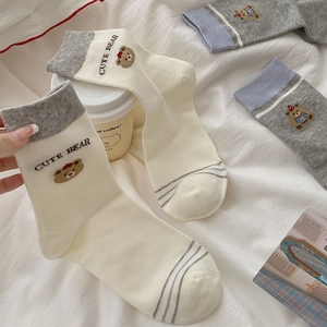 Detail of striped cotton socks with cute bear embroidery and ribbed cuffs in soft tones