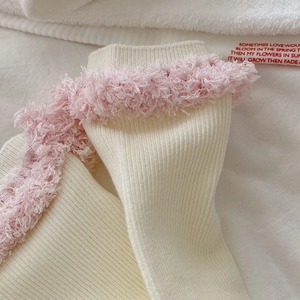 Detail von cremefarbenen Rippstricksocken mit flauschigem rosa Kunstpelz am Knöchel