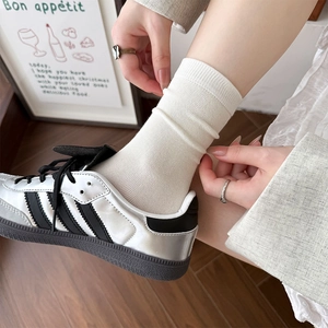 Classic white ribbed crew socks for women styled with vintage sneakers on wooden floor