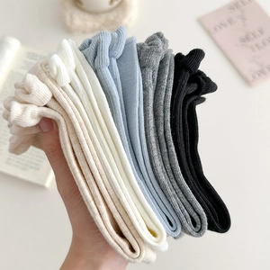 Detail of five-color ribbed knit crew socks with ruffled edges in cream and neutral tones