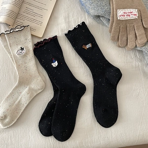 Detail of speckled knit crew socks featuring cute animal embroidery and wavy ruffle cuffs