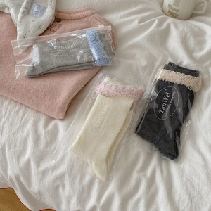 Detailansicht von drei Paar Stricksocken mit flauschigem Fransenbesatz in Geschenkbeutel
