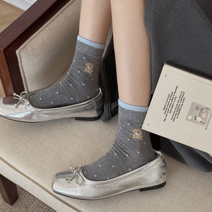 Detail of grey striped crew socks with blue polka dots and a cute brown bear embroidery