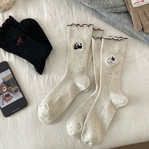 Detail of knit socks with wavy lace cuffs and cute cartoon cat embroidery in autumn style