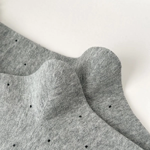 Close-up of grey knitted mid-calf socks with black polka dots and cotton texture