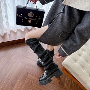 Detailed knit texture of dark grey leg warmers in a thick vertical ribbed weave pattern