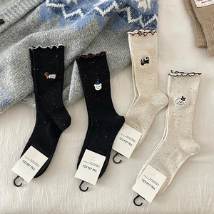 Detail of ribbed socks with scalloped edges and cute animal embroidery on a cozy background