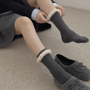Dunkelgraue Strick-Socken mit weißem Kunstfellbesatz und Ballerinas auf strukturiertem Teppich