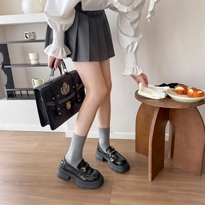 Close-up of black patent leather platform loafers with preppy style school bag and accessories